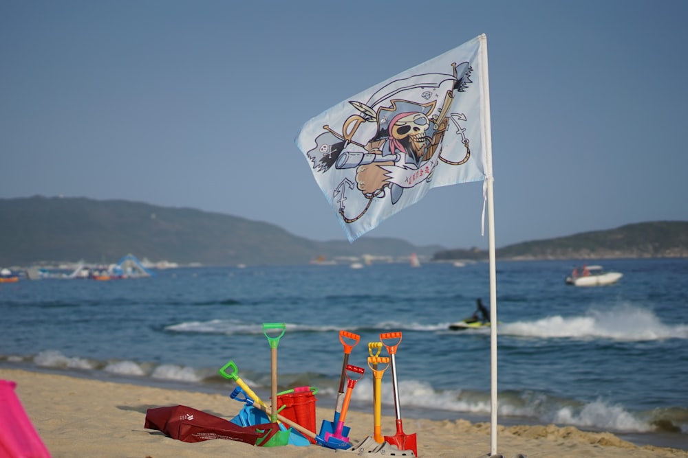 eine Flagge mit einem Bild eines Skeletts darauf an einem Strand