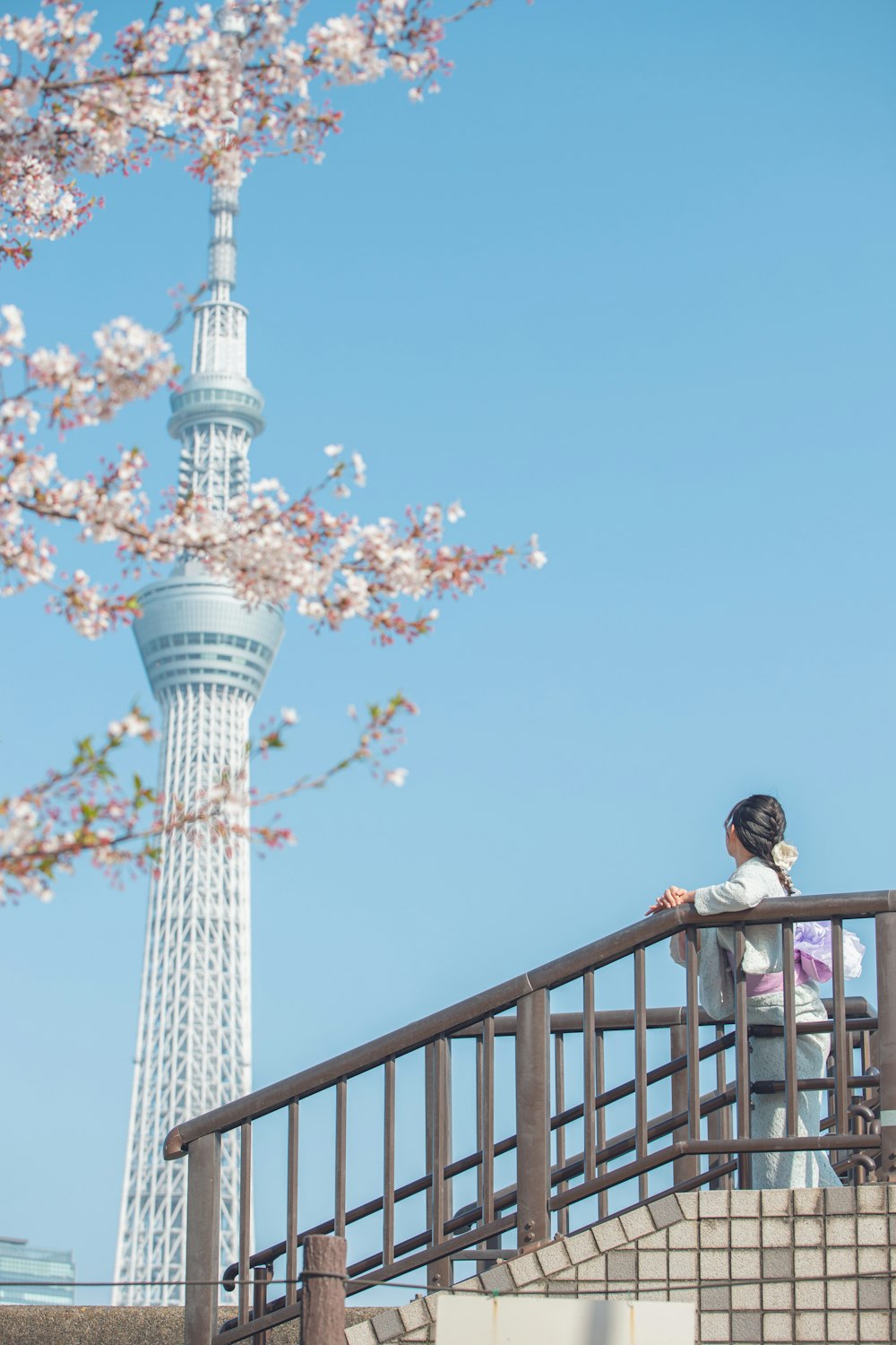 a woman standing on a bridge next to a tall tower