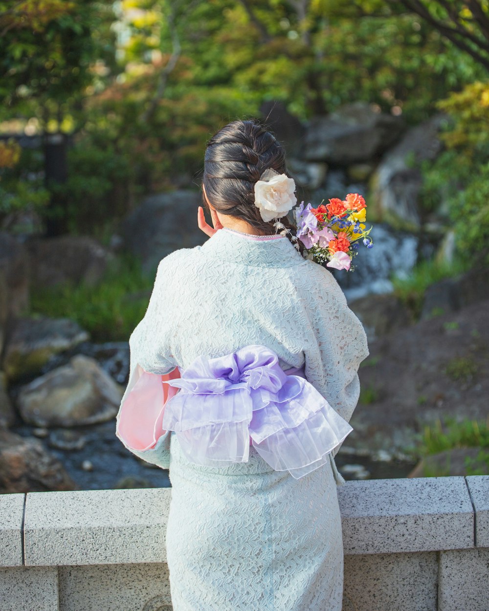 a woman in a kimono is looking at a waterfall