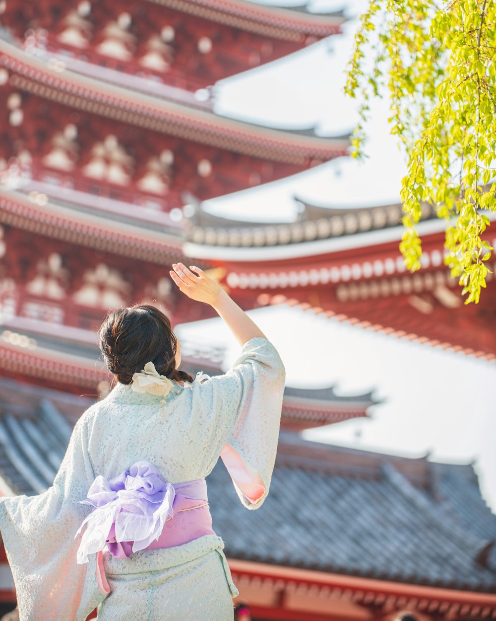 Una mujer con un kimono parada frente a una pagoda