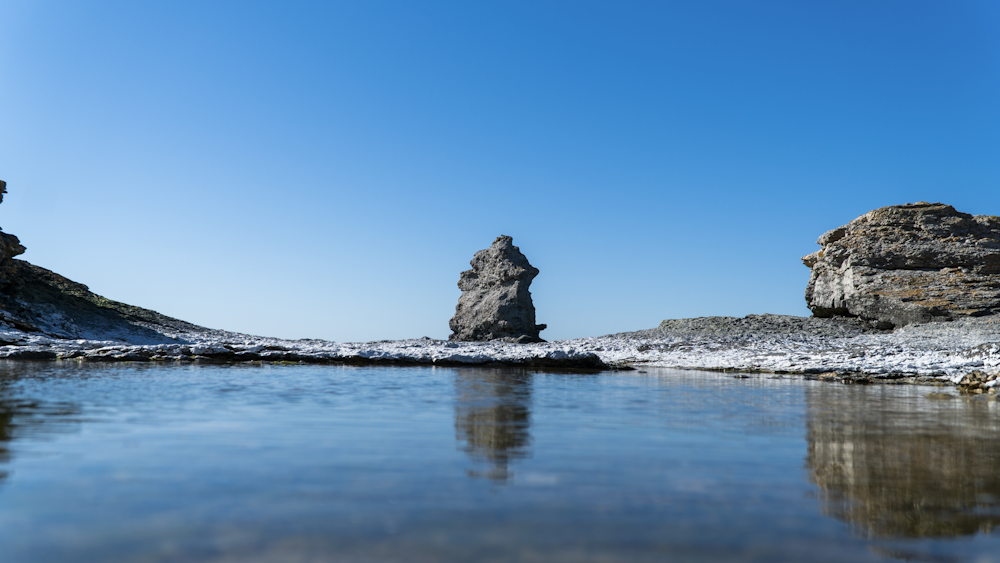 a body of water surrounded by rocks and snow