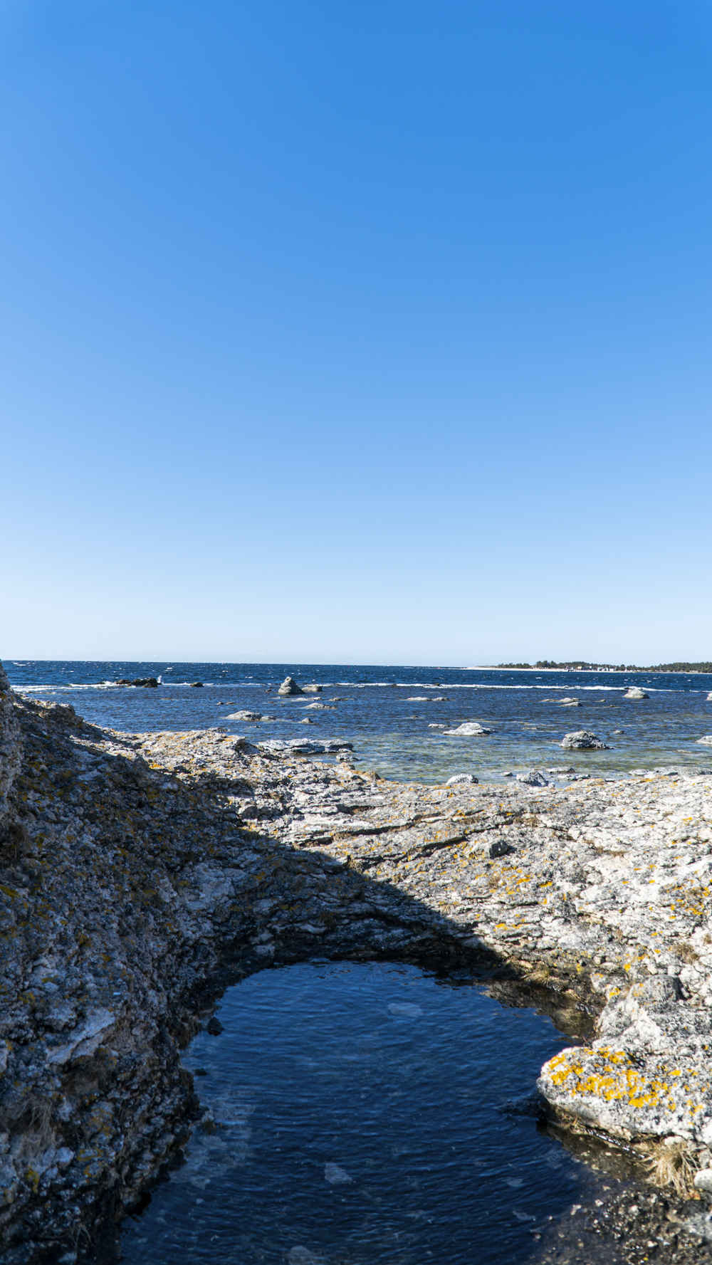 um homem de pé no topo de um penhasco rochoso ao lado do oceano