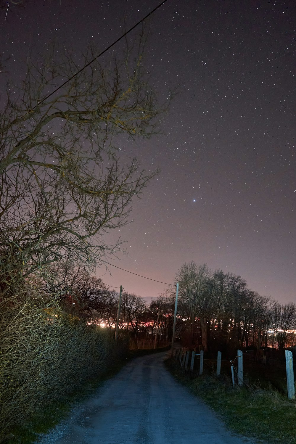 a dirt road at night with stars in the sky