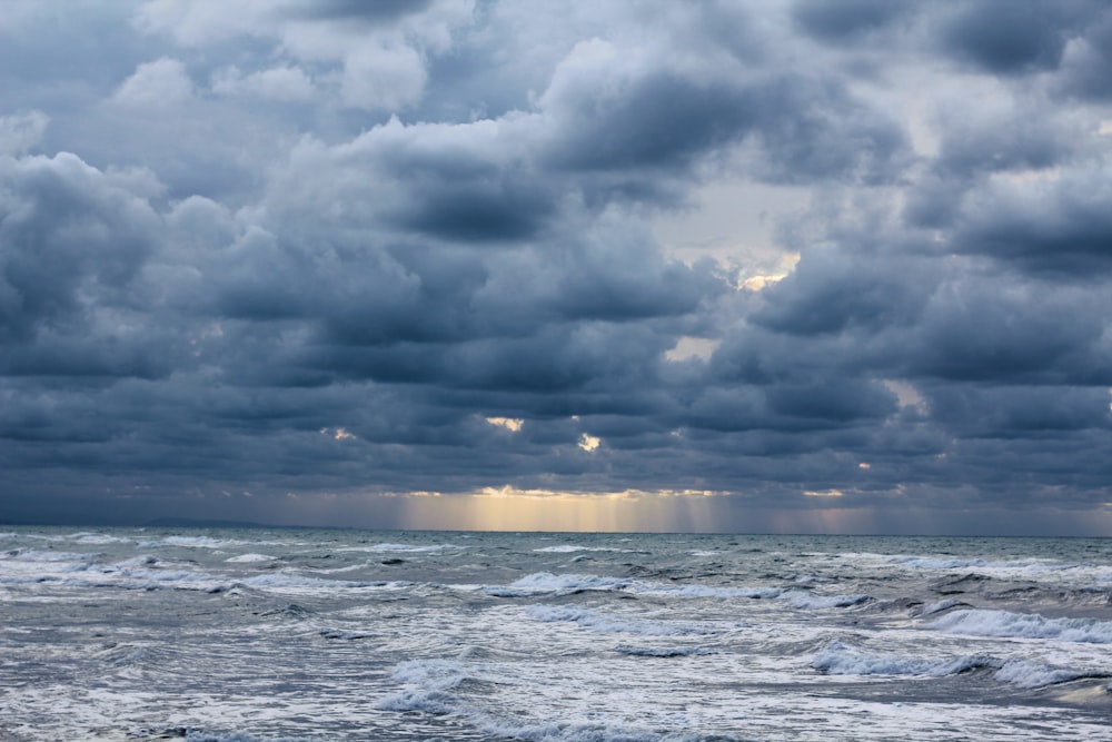 a cloudy sky over the ocean with waves