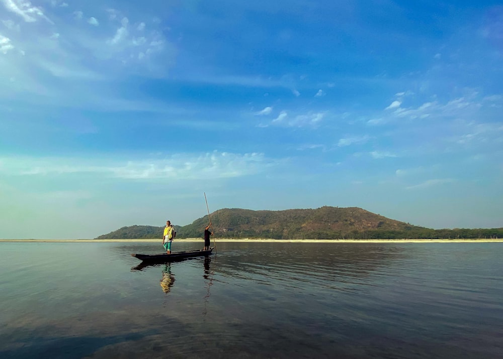 a man standing on top of a boat in a lake