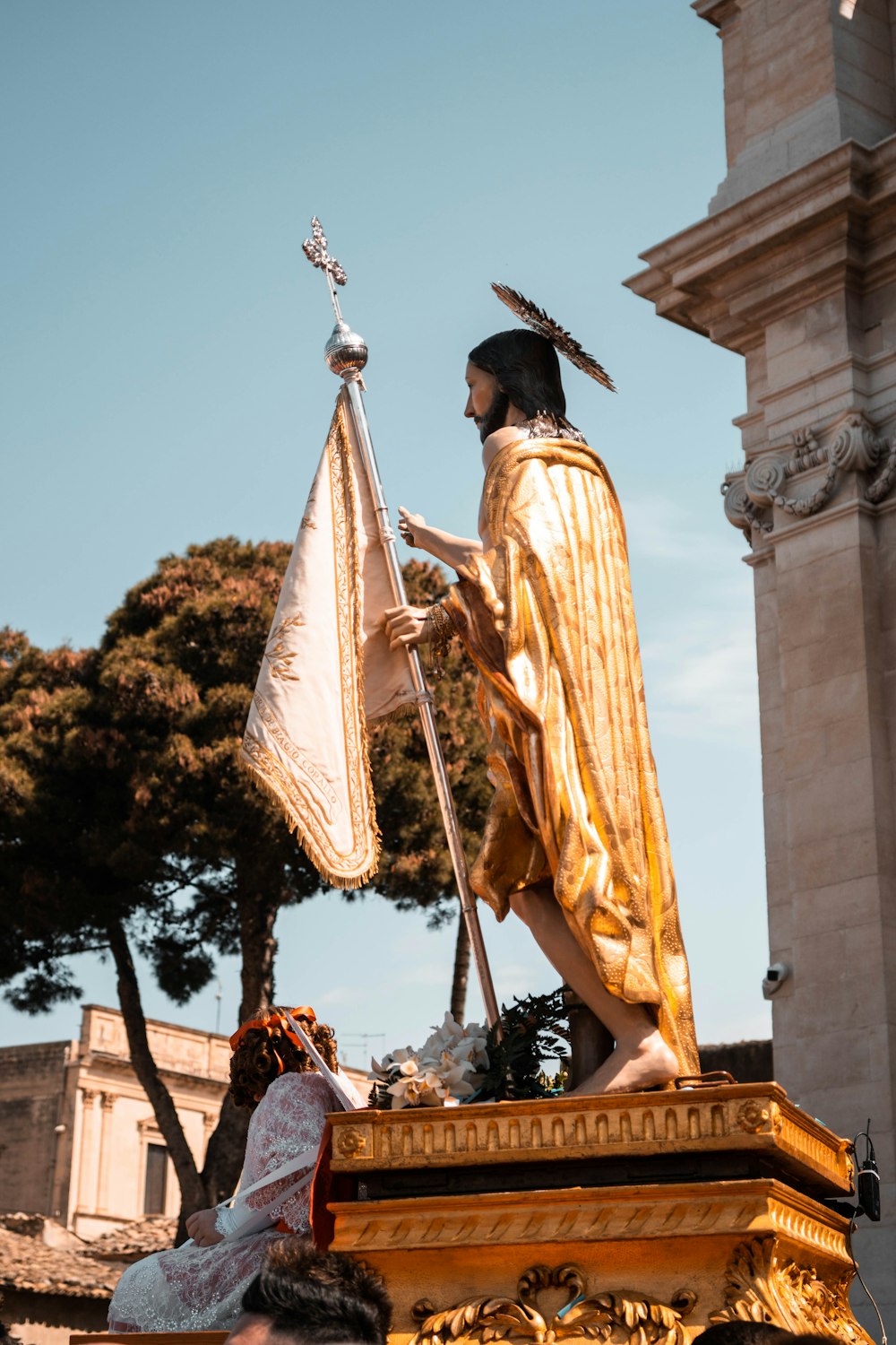 Una estatua de un hombre sosteniendo una bandera frente a un edificio