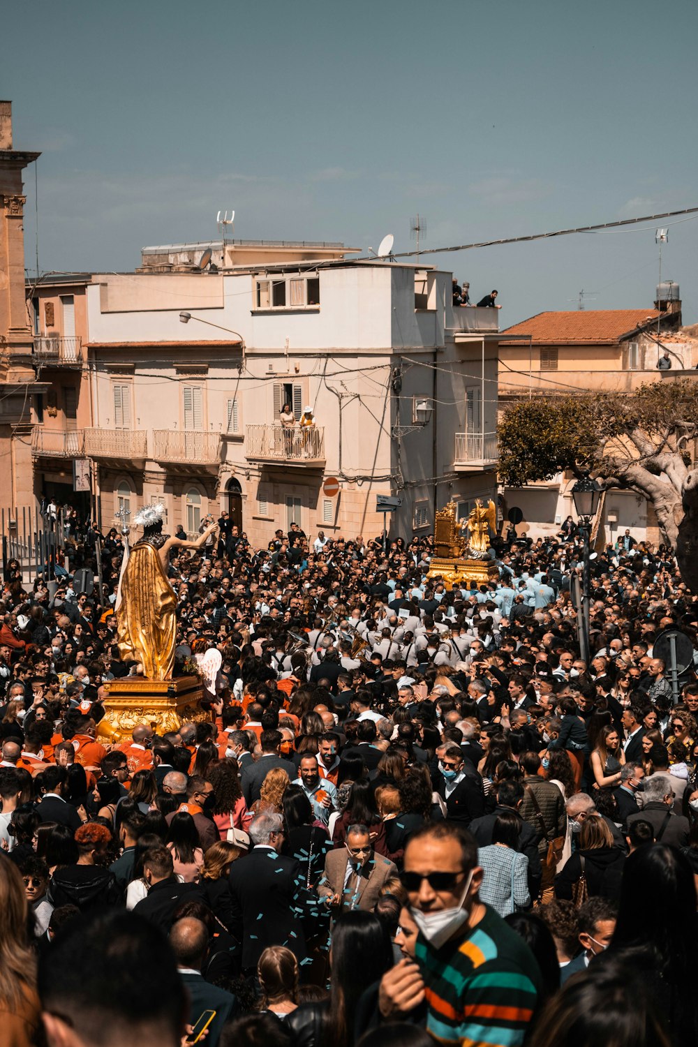 a large crowd of people standing around a golden statue