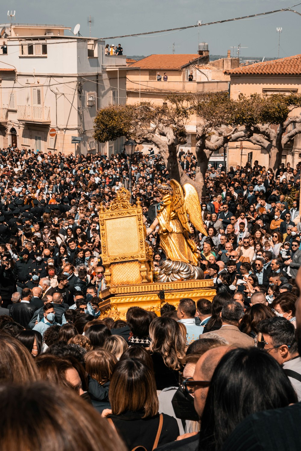 a crowd of people standing around a golden statue