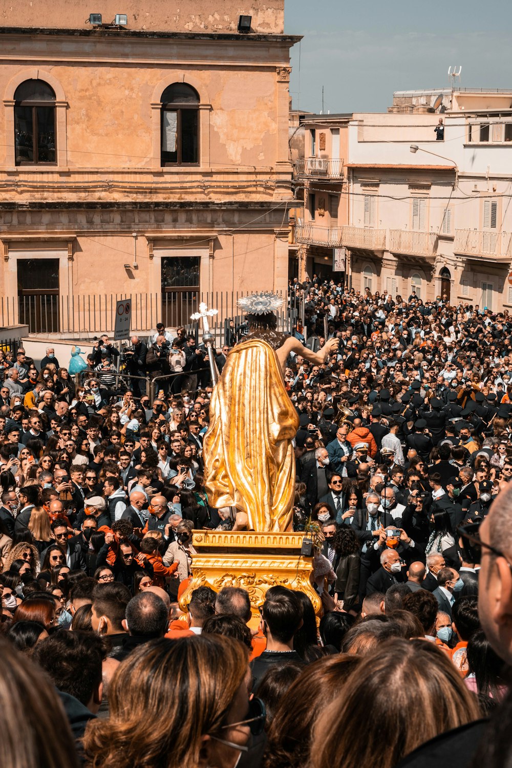 a large crowd of people standing around a golden statue
