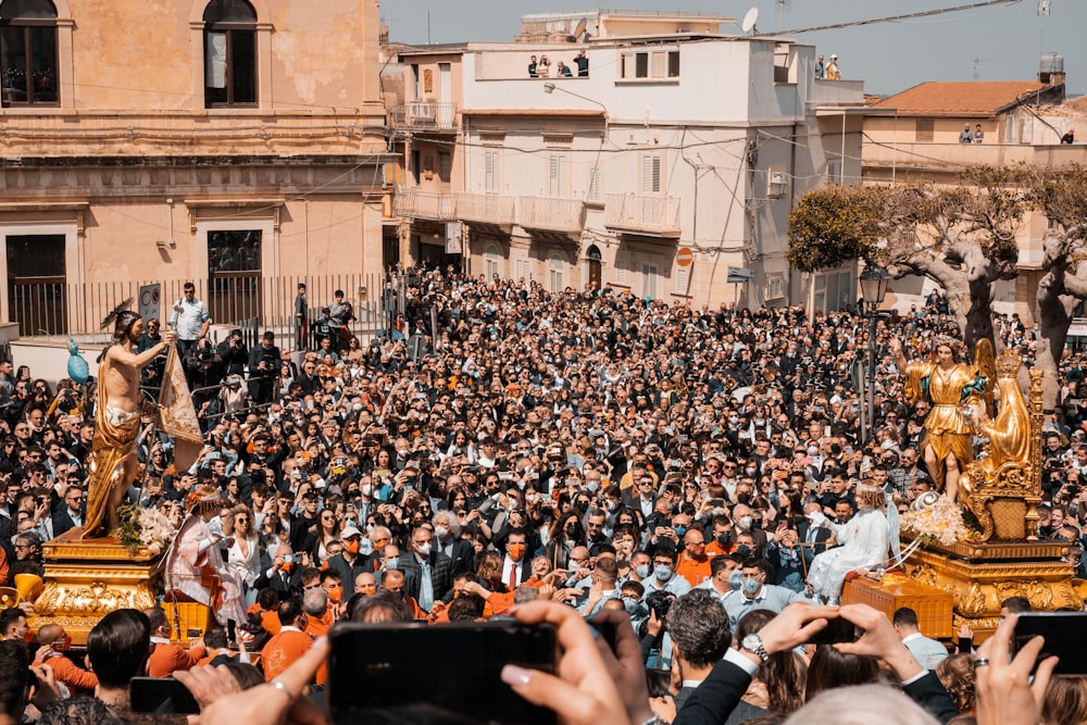 a large crowd of people standing around a statue