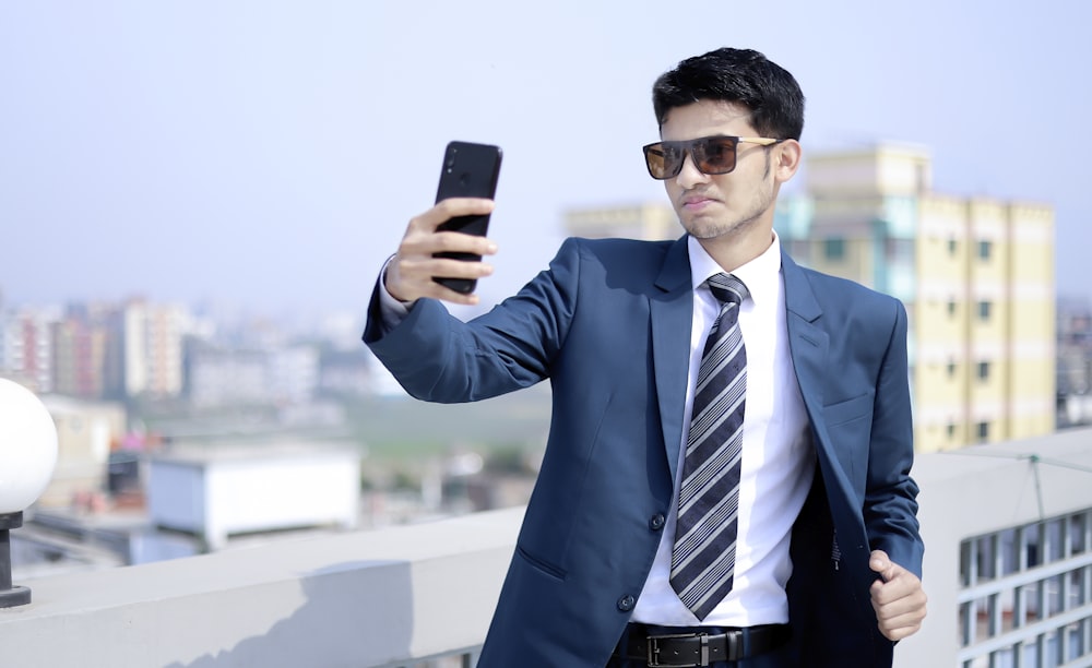 a man in a suit taking a picture with a cell phone