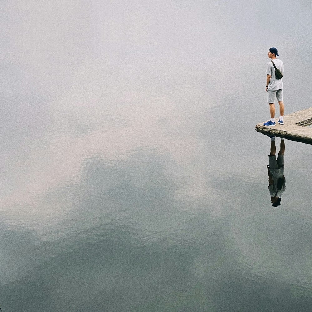 a man standing on a dock next to a body of water
