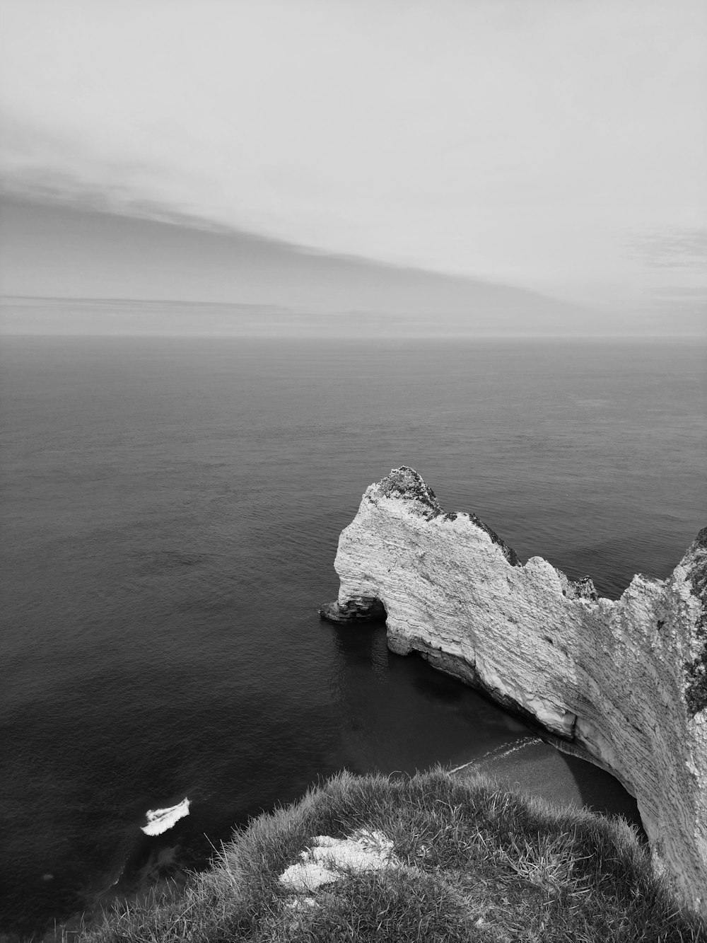 Una foto en blanco y negro de un acantilado y un cuerpo de agua