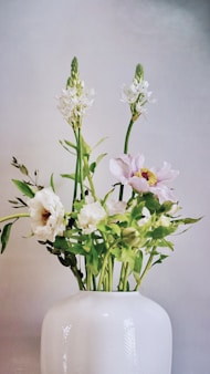 a white vase filled with white and pink flowers