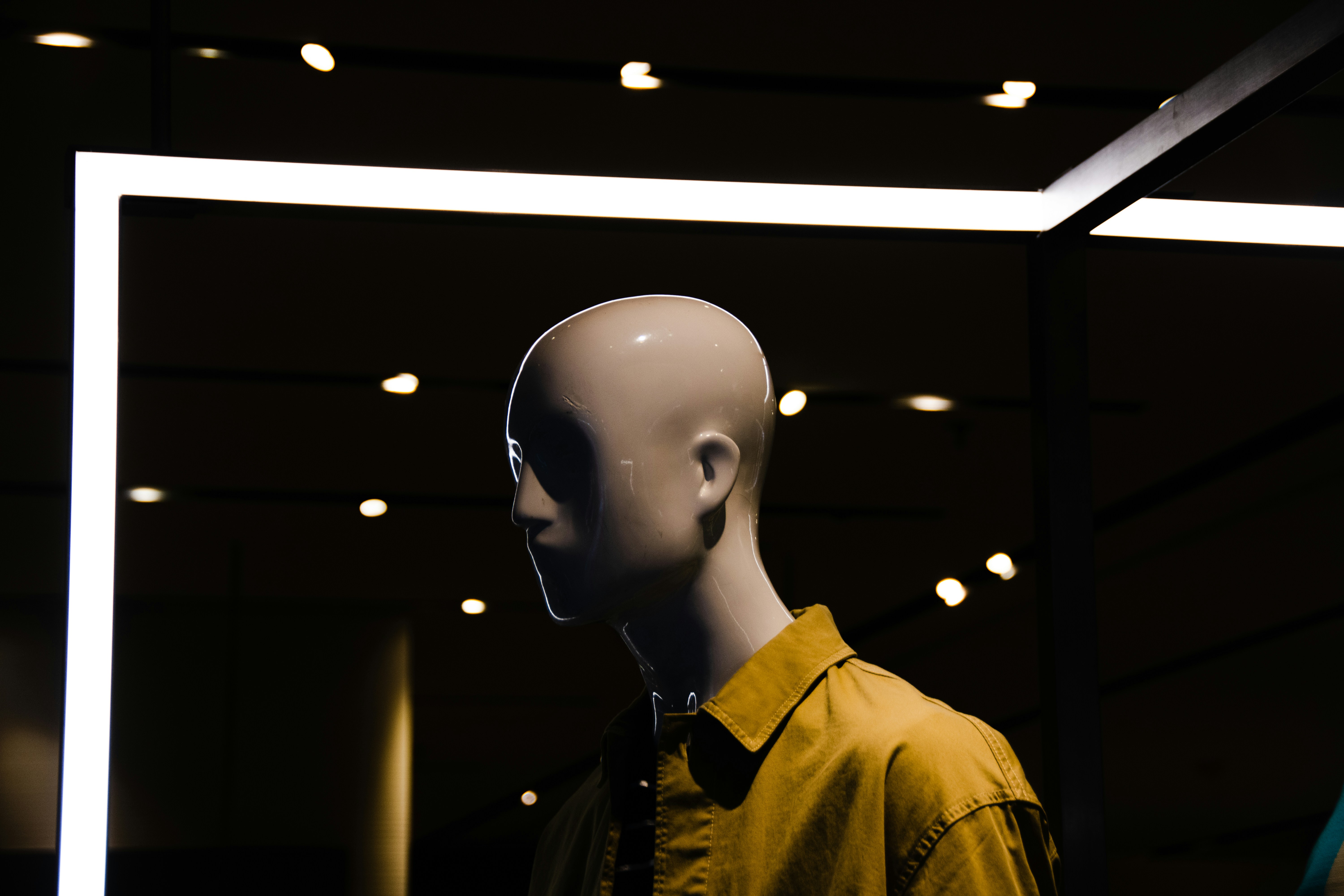 Branimo mannequin display featuring a yellow shirt in a dark room