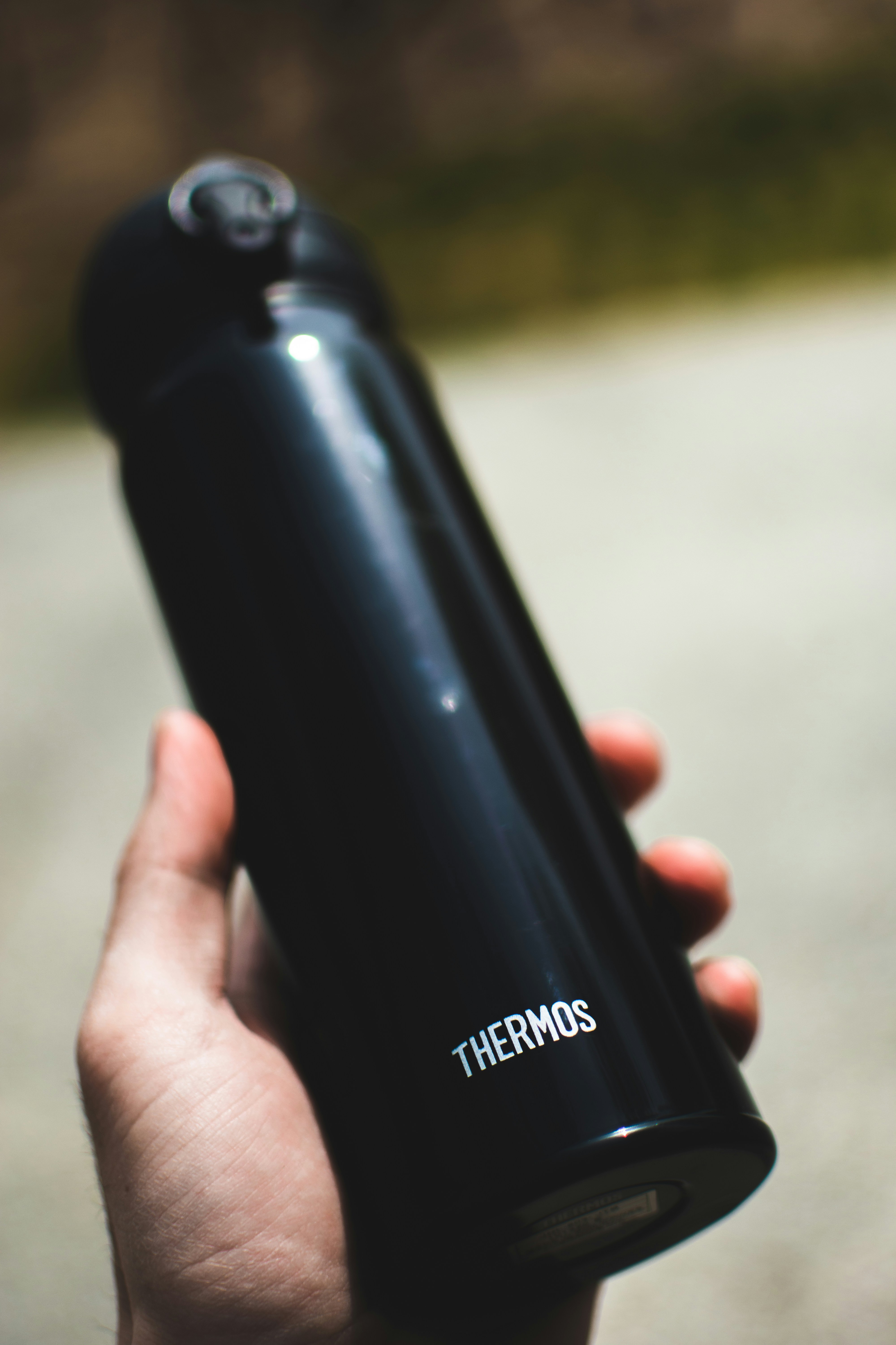 a person holding a black thermos bottle in their hand