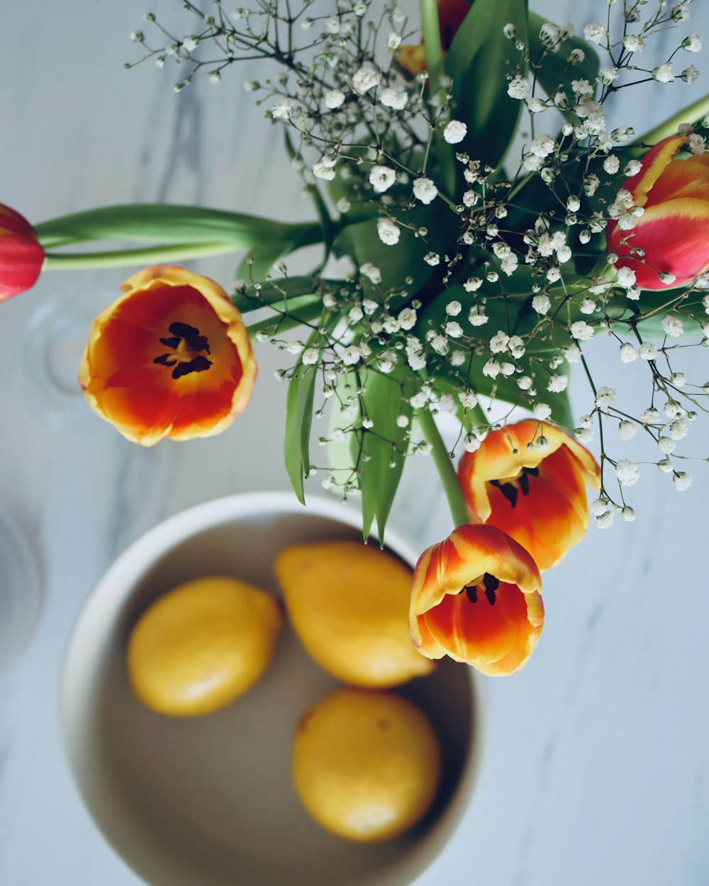 a white bowl filled with yellow and red tulips