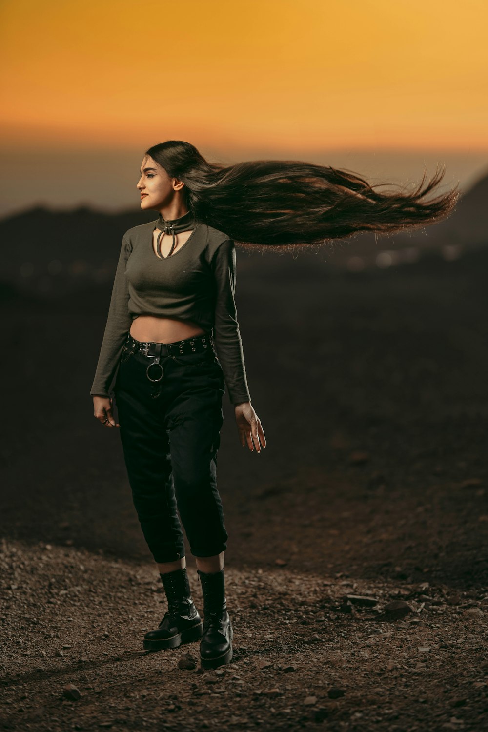 a woman with long hair walking down a dirt road