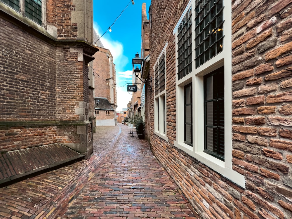 a narrow brick street with a bench between two buildings
