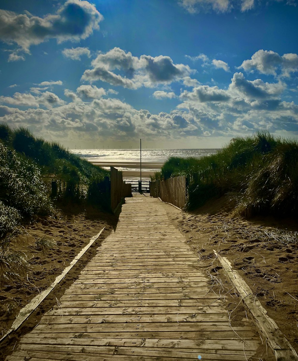 a wooden walkway leading to the beach under a cloudy sky