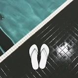 a pair of white flip flops sitting on a tiled floor