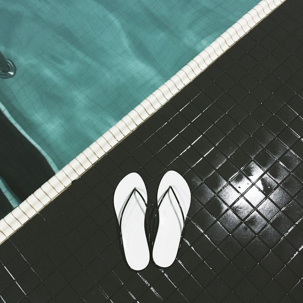 a pair of white flip flops sitting on a tiled floor