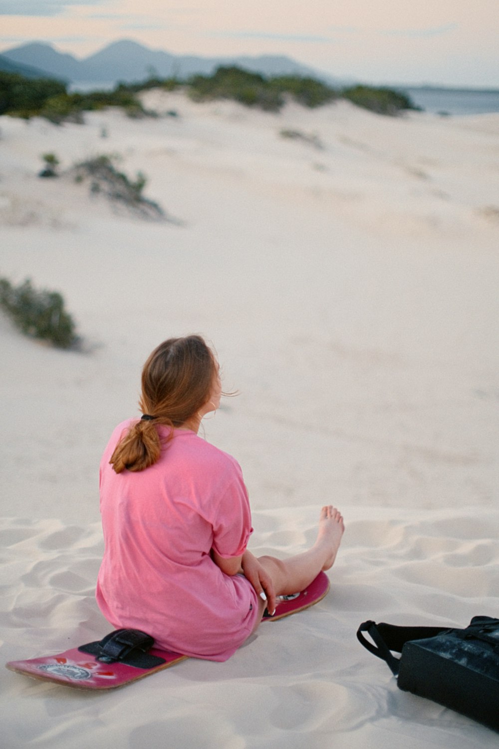 Une femme assise dans le sable avec une planche à neige