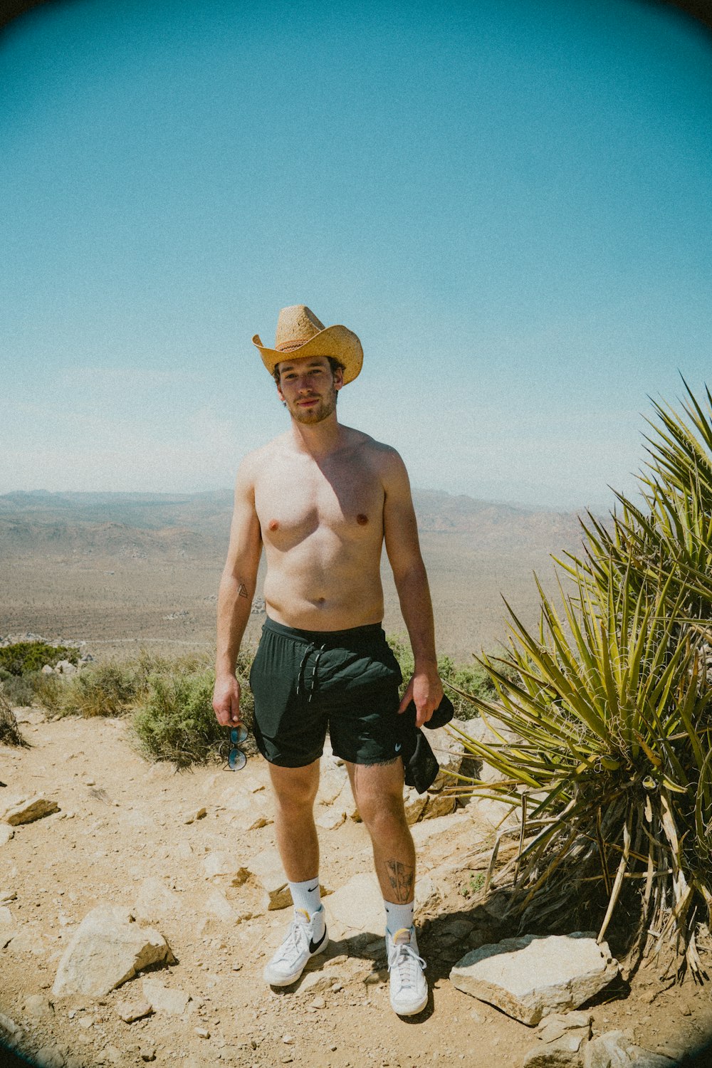 a man in a cowboy hat standing in the desert