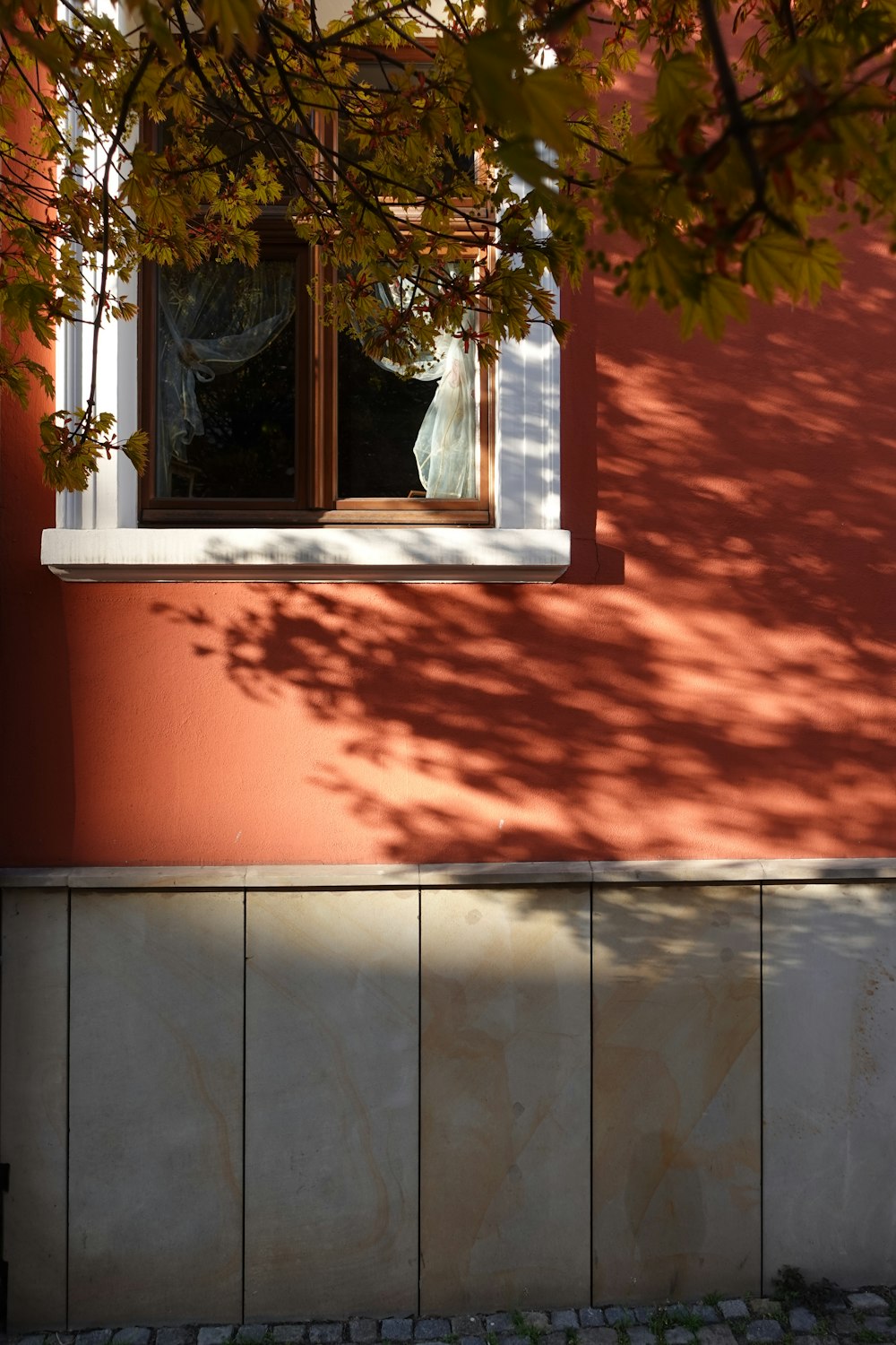 a red building with a window and a tree