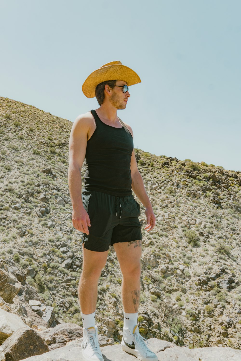 a man wearing a yellow hat standing on a rock