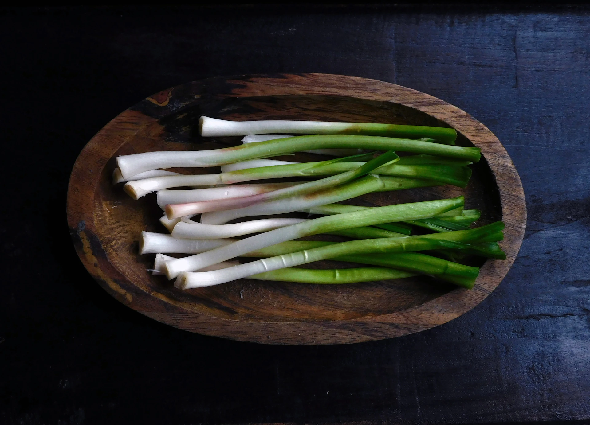 a wooden bowl filled with green and white onions