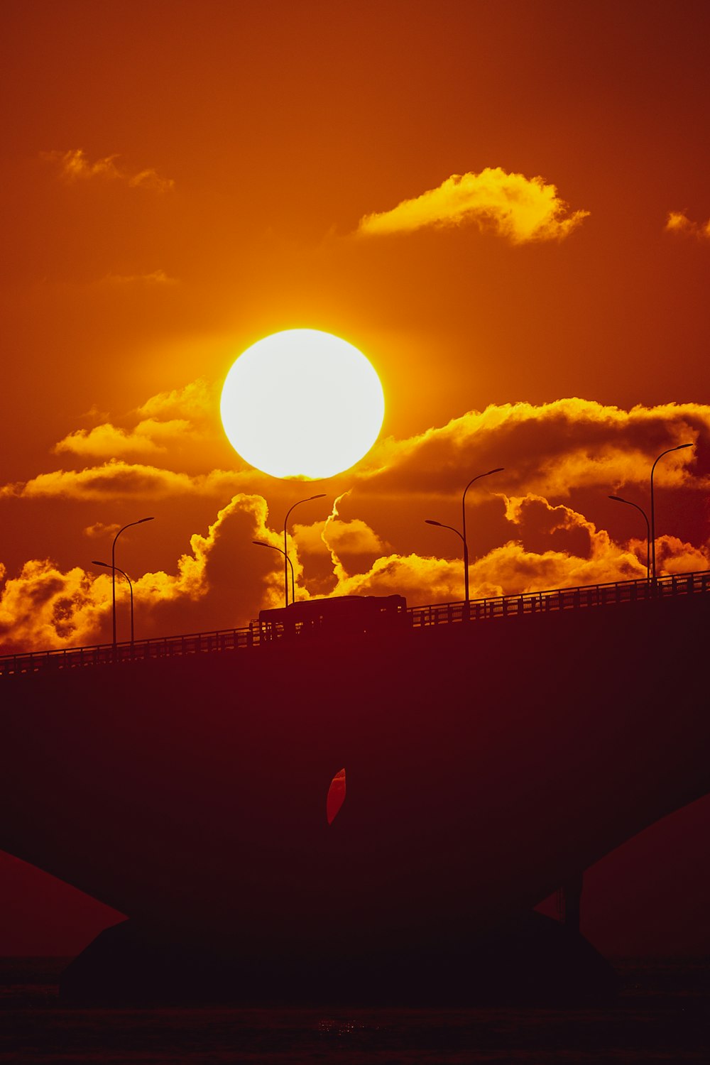 the sun is setting over a bridge in the sky