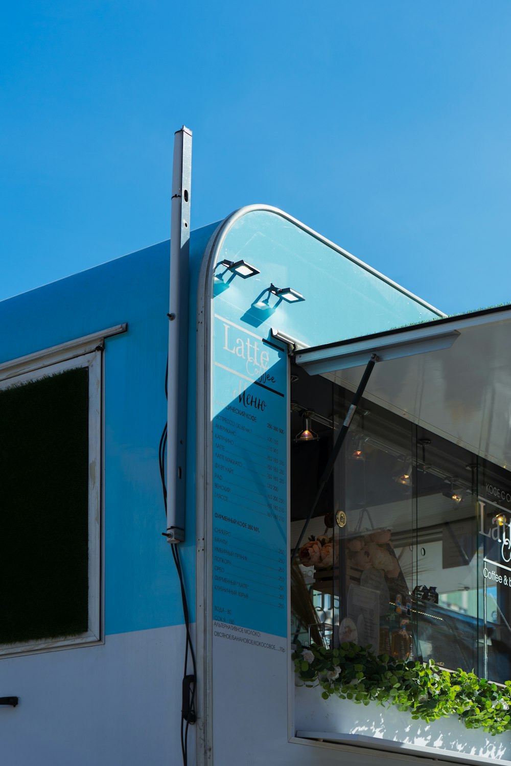 a blue and white food truck with plants growing out of it