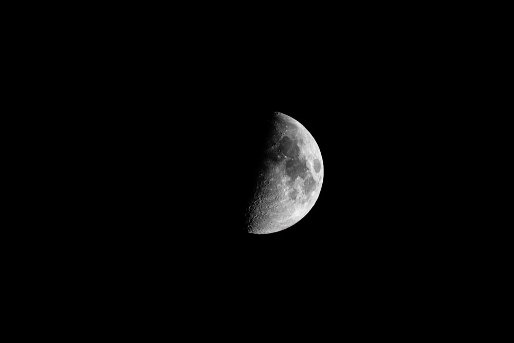 a half moon is seen in the dark sky