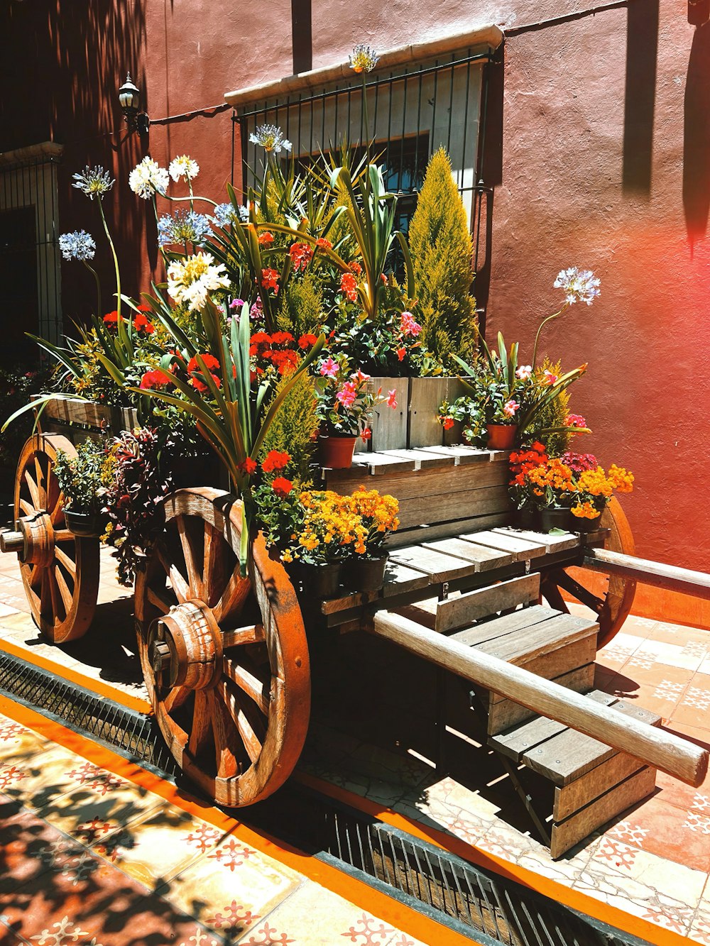 a wooden cart with flowers in it sitting on a sidewalk