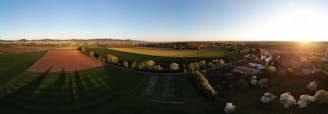 A panoramic view of a sunset over a rural village with musicians setting up for an evening jam session.