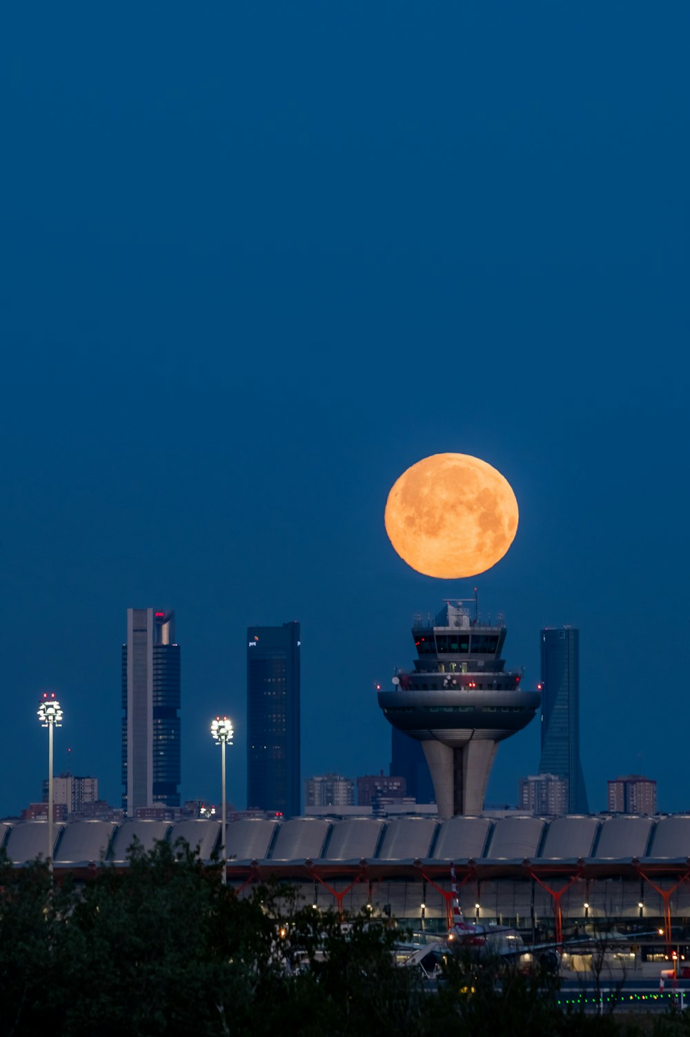 a full moon rises over a city skyline