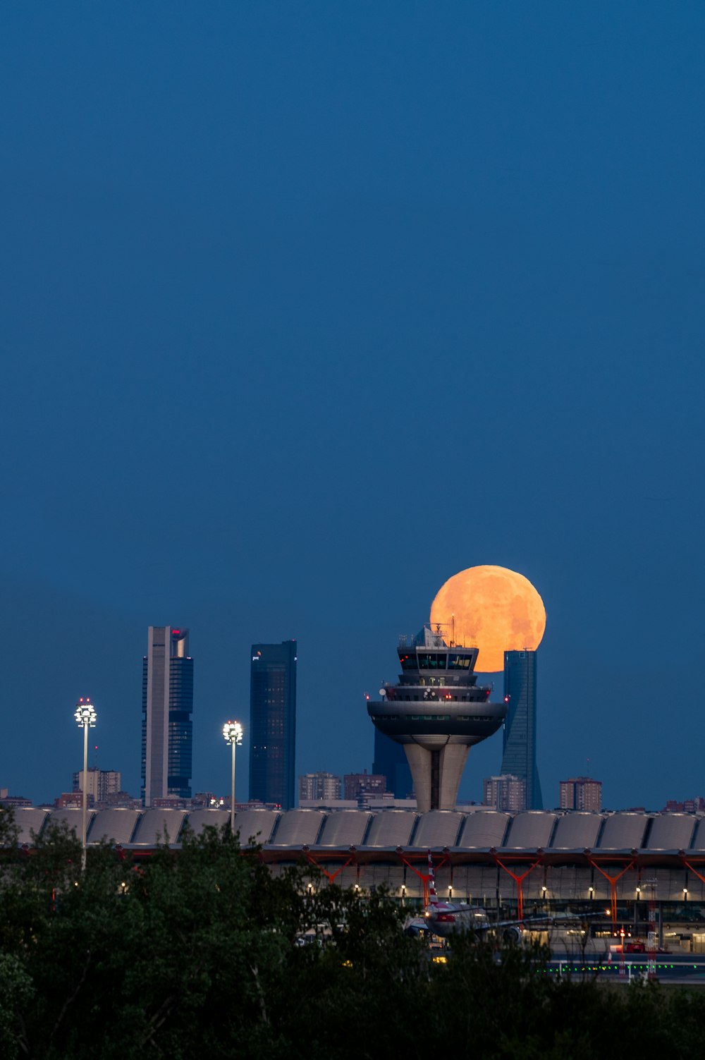 a full moon rises over a city skyline