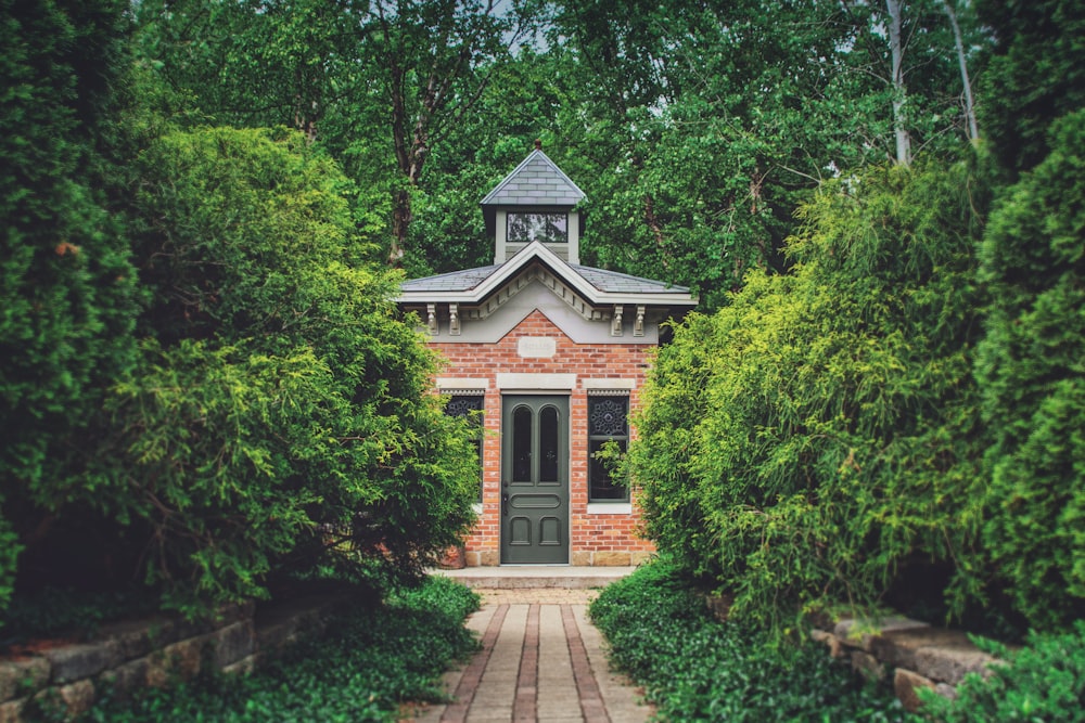 a small brick building surrounded by trees and bushes