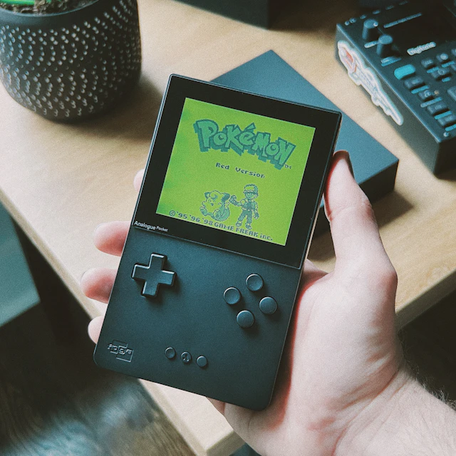 A hand holding an Analogue Pocket handheld playing Pokemon Red