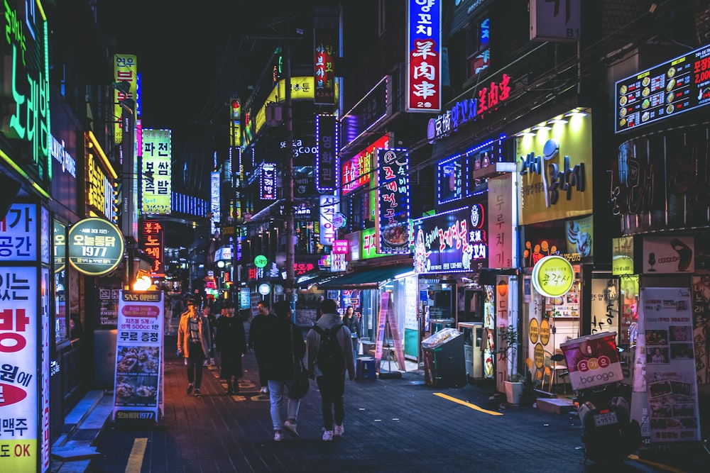 a group of people walking down a street at night