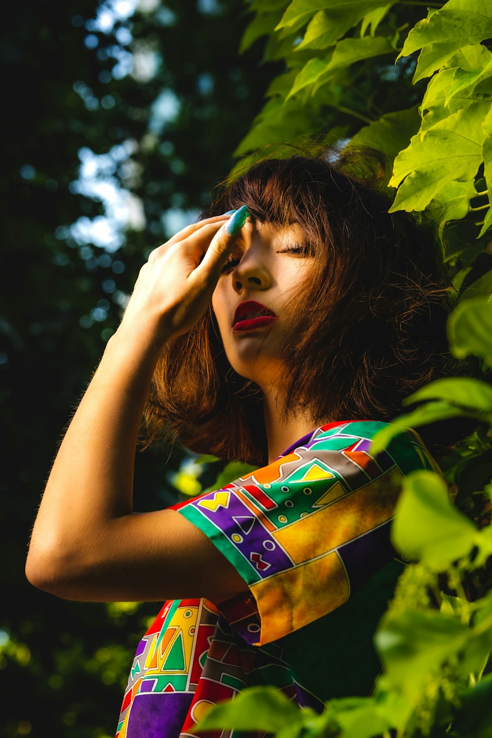 a woman in a colorful dress is holding her hand up to her face