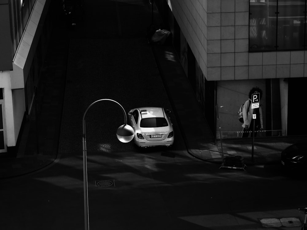 a white car parked on a street next to a tall building