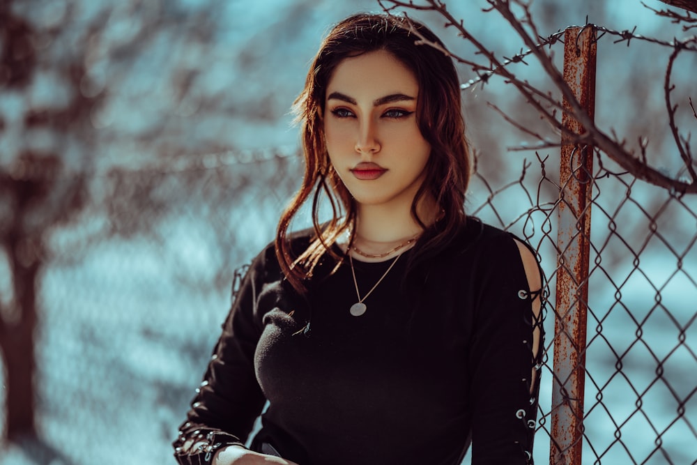 a woman standing next to a chain link fence