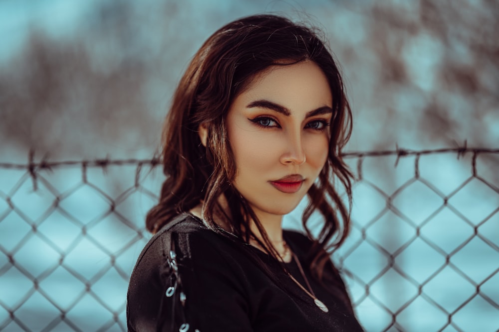 a woman standing in front of a chain link fence