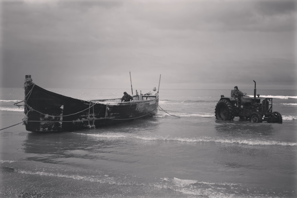 a boat sitting on top of a beach next to a tractor