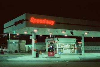 a gas station at night with a neon sign