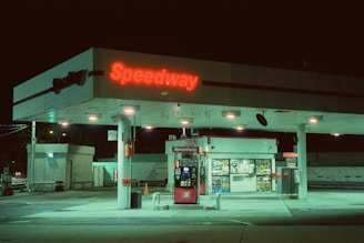 a gas station at night with a neon sign