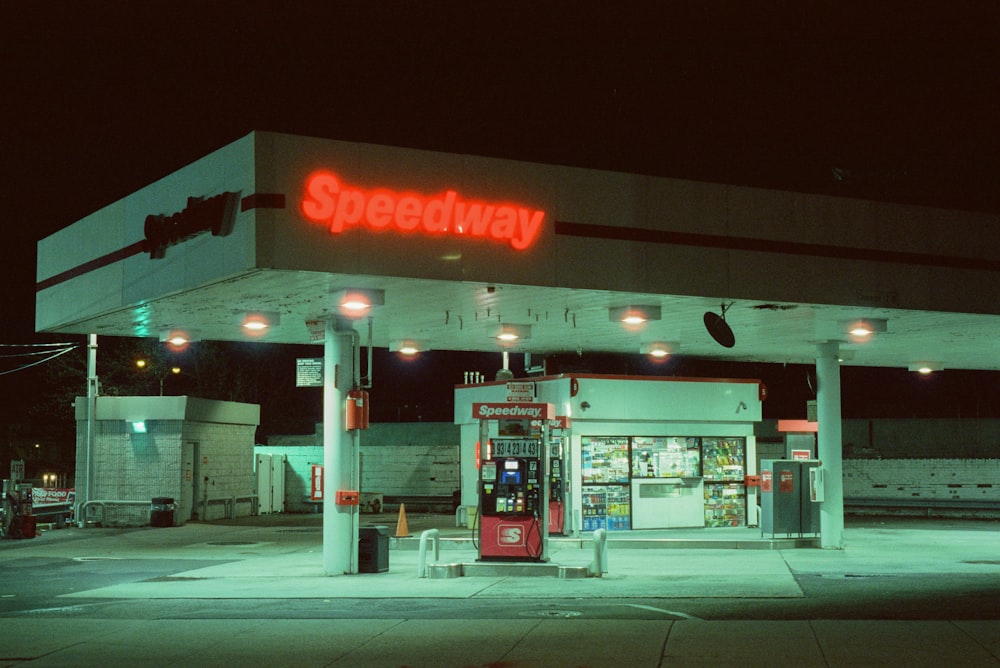 a gas station at night with a neon sign