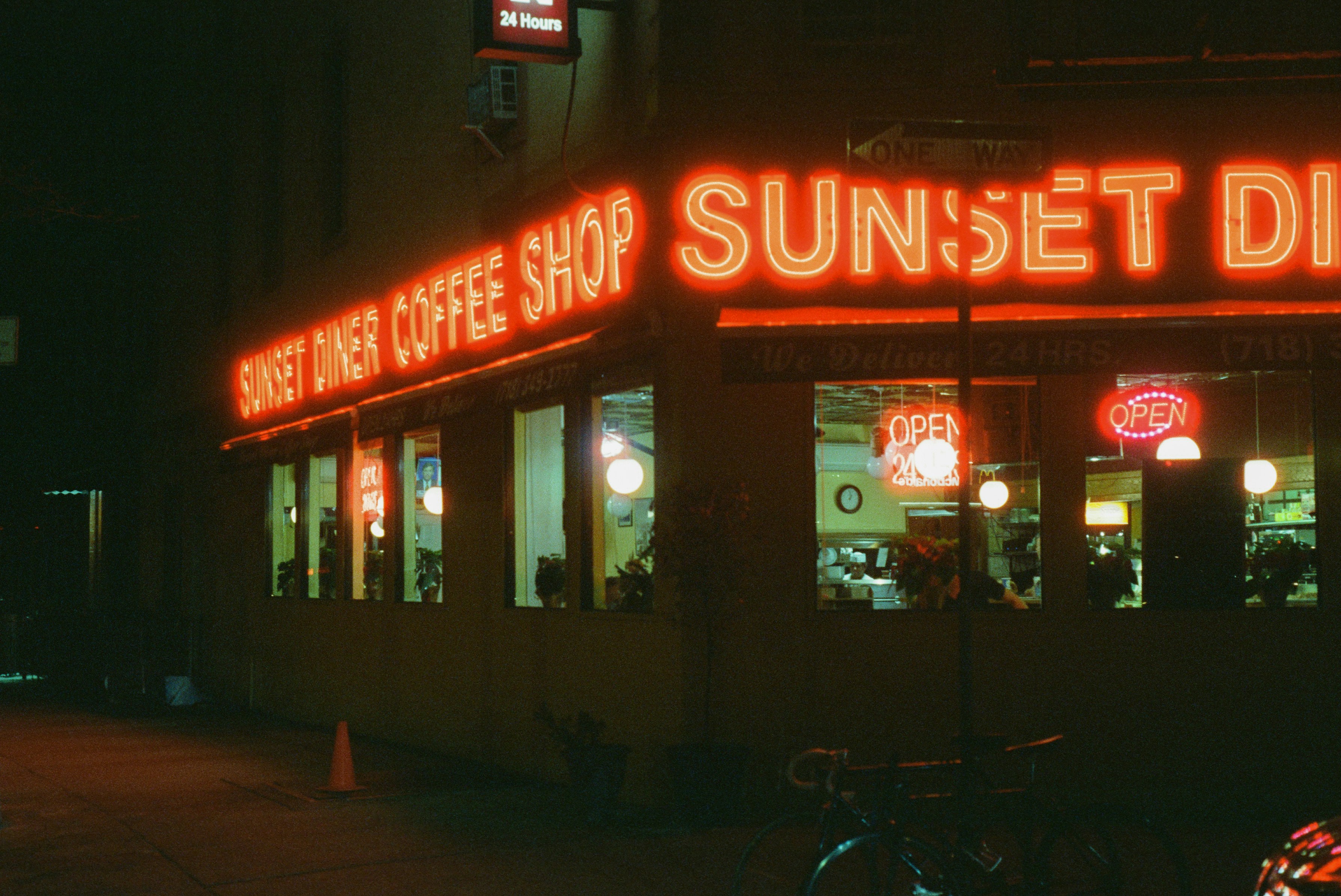 a neon sign on the side of a building, Sunset Diner photographed on Cinestill 800T.